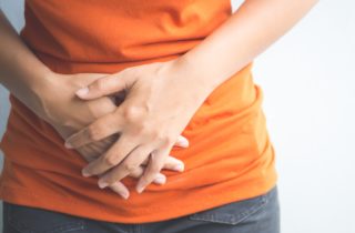 women experiencing bloating, holding her stomach