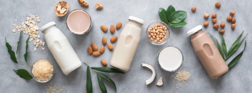 bottles of milk alternatives laid out on a table.