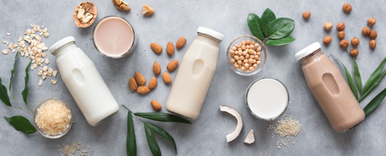 bottles of milk alternatives laid out on a table.