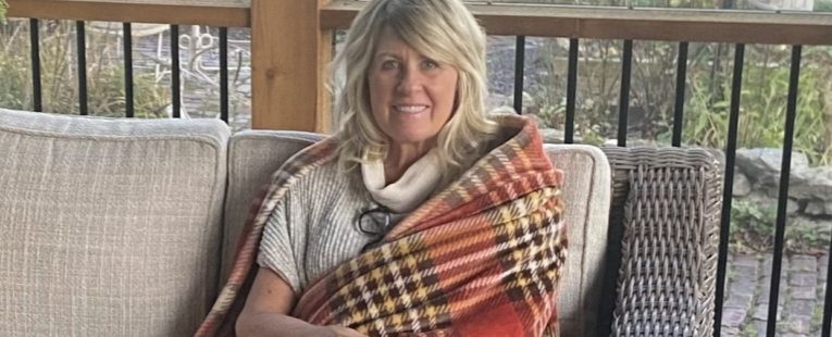 Misty Barnes sits on a patio with a blanket.