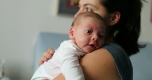 Mother holding her newborn baby with hiccups.