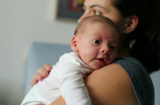 Mother holding her newborn baby with hiccups.