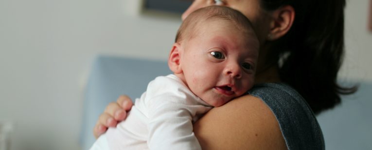 Mother holding her newborn baby with hiccups.