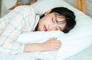 young woman sleeps on a white pillow with a blanket