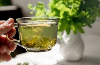 hand holds a clear cup filled with tea