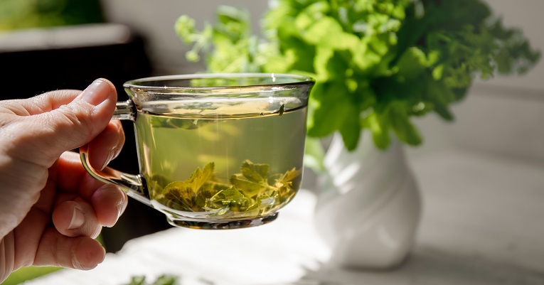 hand holds a clear cup filled with tea