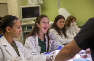 high school students in medical lab coats smile in a lab