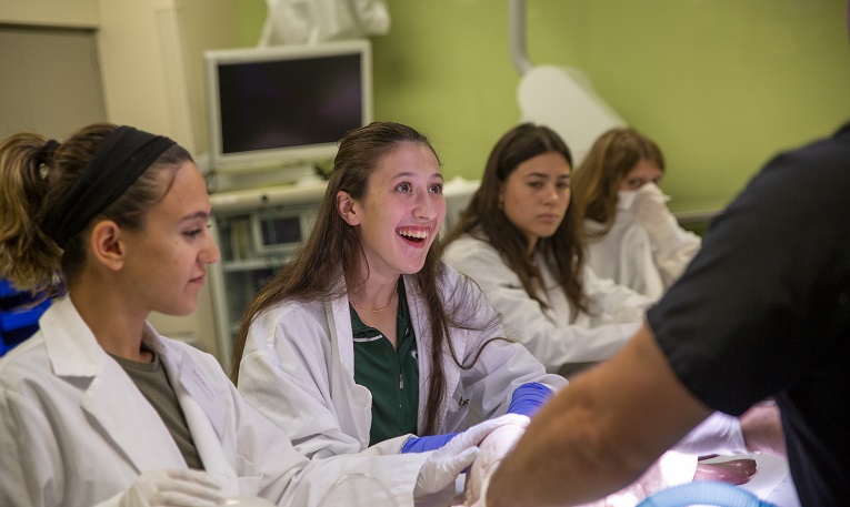 high school students in medical lab coats smile in a lab