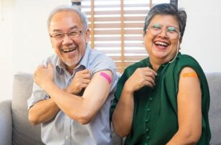 senior asian couples smile with bandages on their upper arms