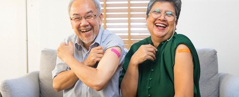 senior asian couples smile with bandages on their upper arms