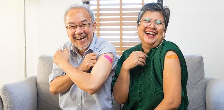 senior asian couples smile with bandages on their upper arms