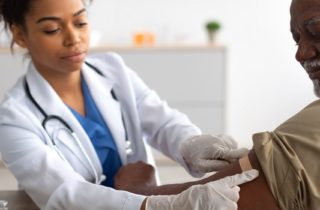 young female provider places a bandage over a male patients arm after a vaccine